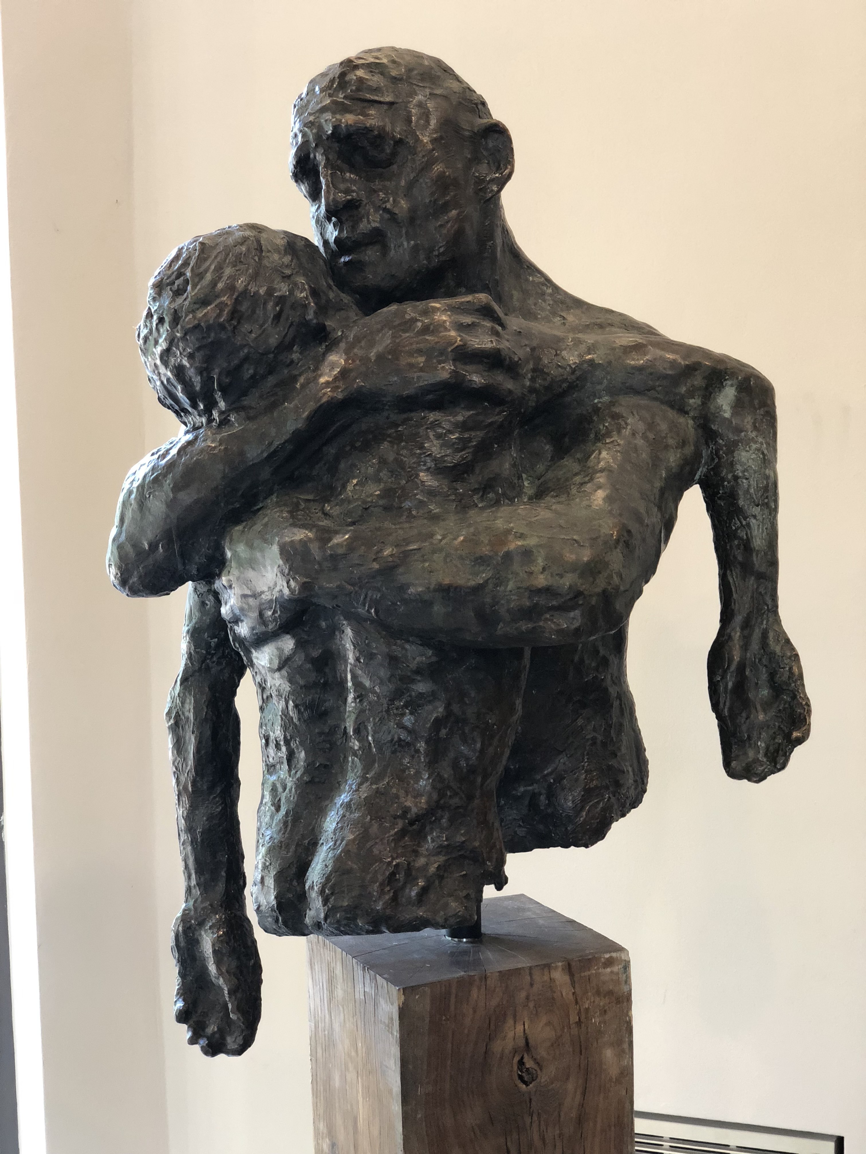 A bronze sculpture of a figure carrying another figure across its shoulder