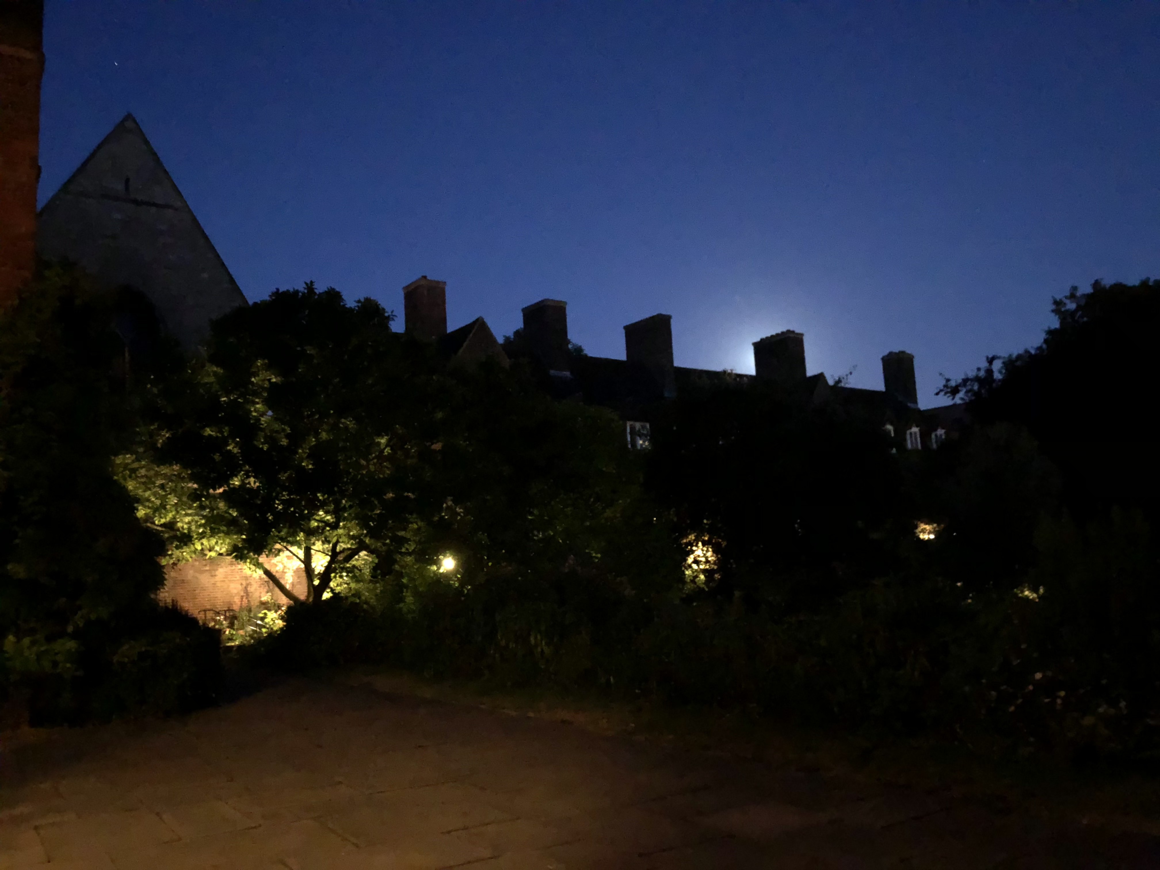 The same court after dark, moon rising over the chimneys
