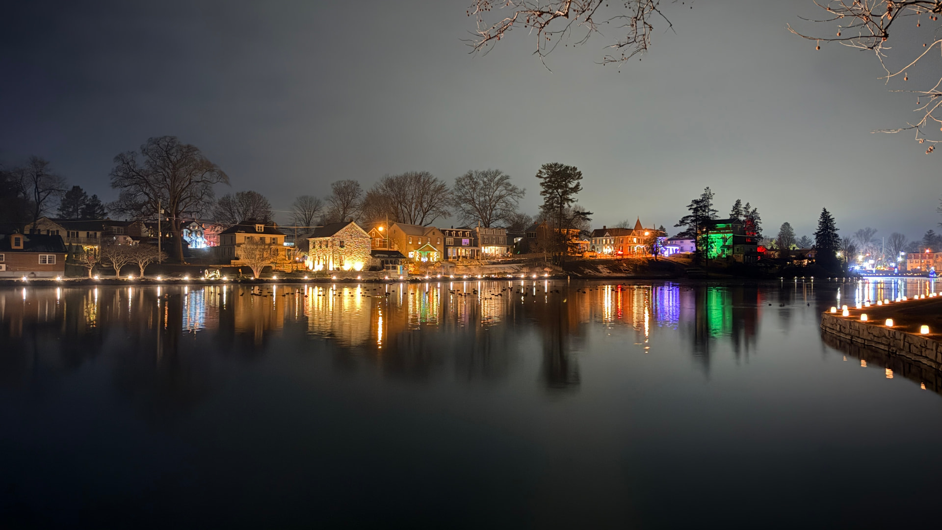 A town reflected in still water at night, the shoreline lined with small lights