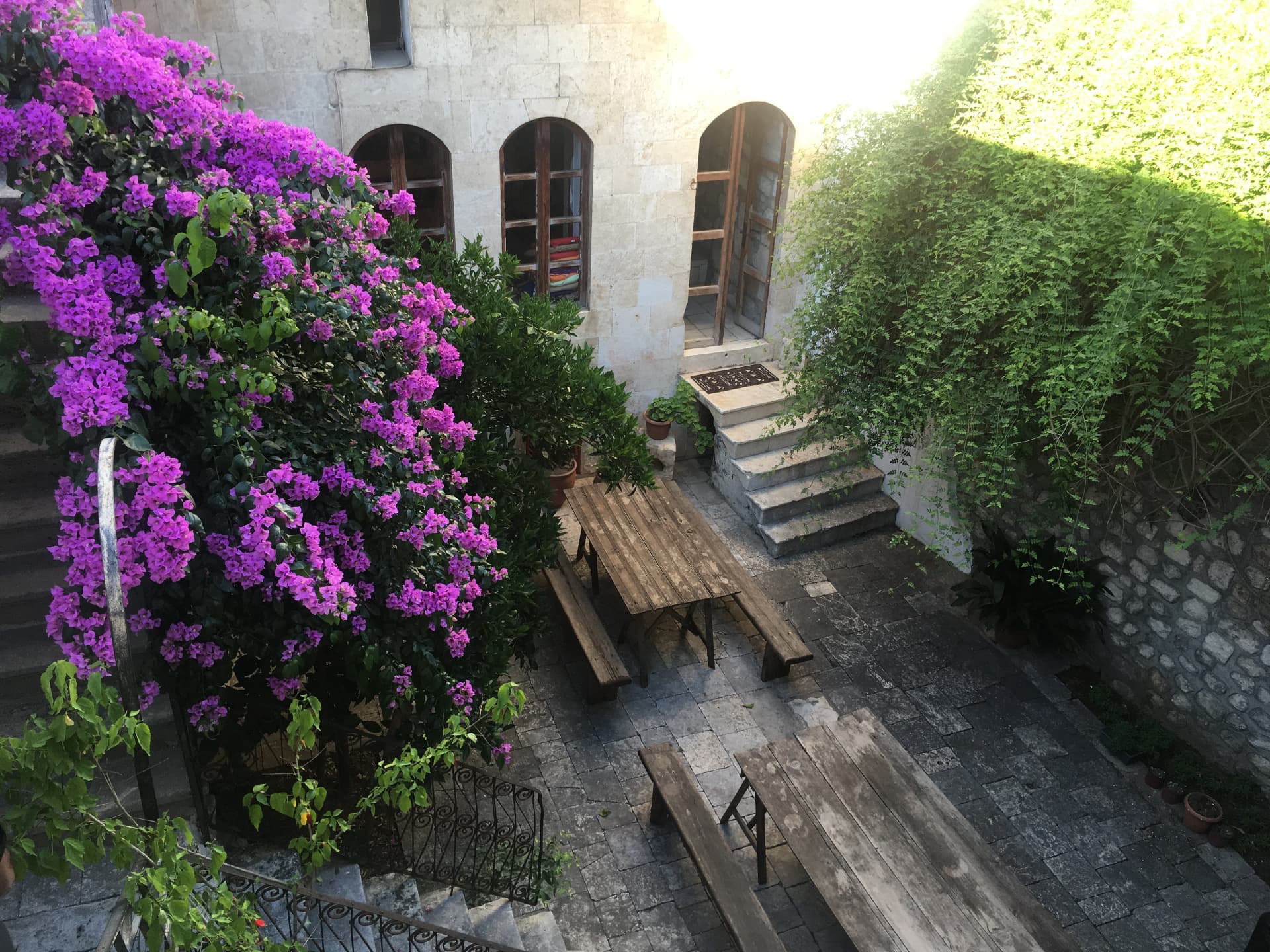 Bougainvillea spilling over a stone courtyard with a worn wooden table