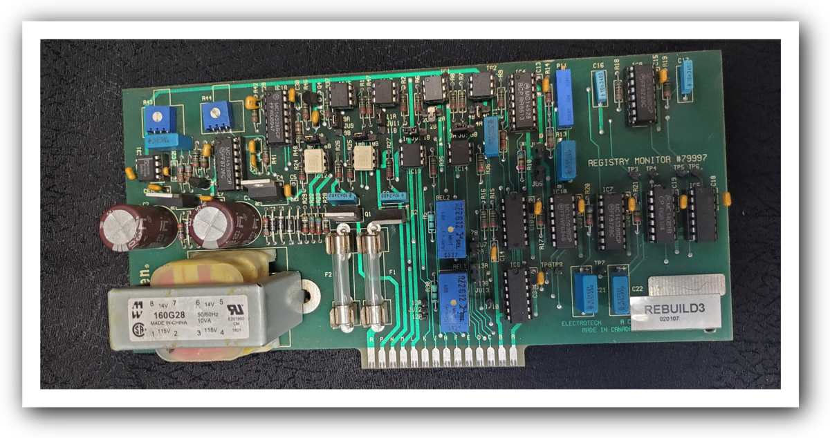 A green circuit board labelled Registry Monitor #79997, hand-populated with capacitors, fuses and integrated circuits