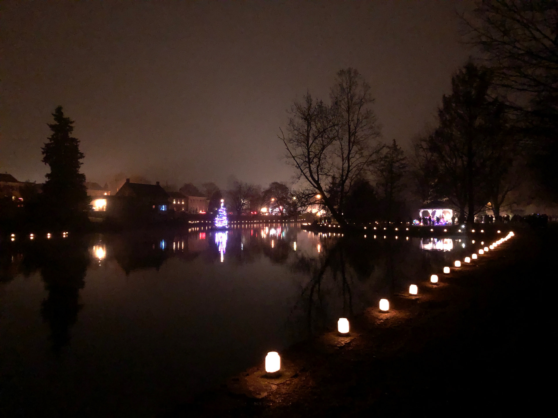 Luminaries lining a pond at night, lights reflected on still water