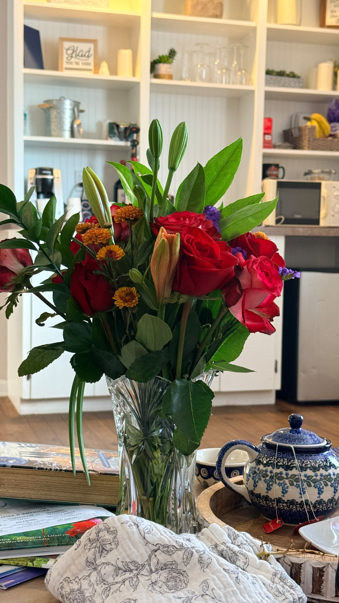 A crystal vase of red roses and yellow chrysanthemums on a welcoming table