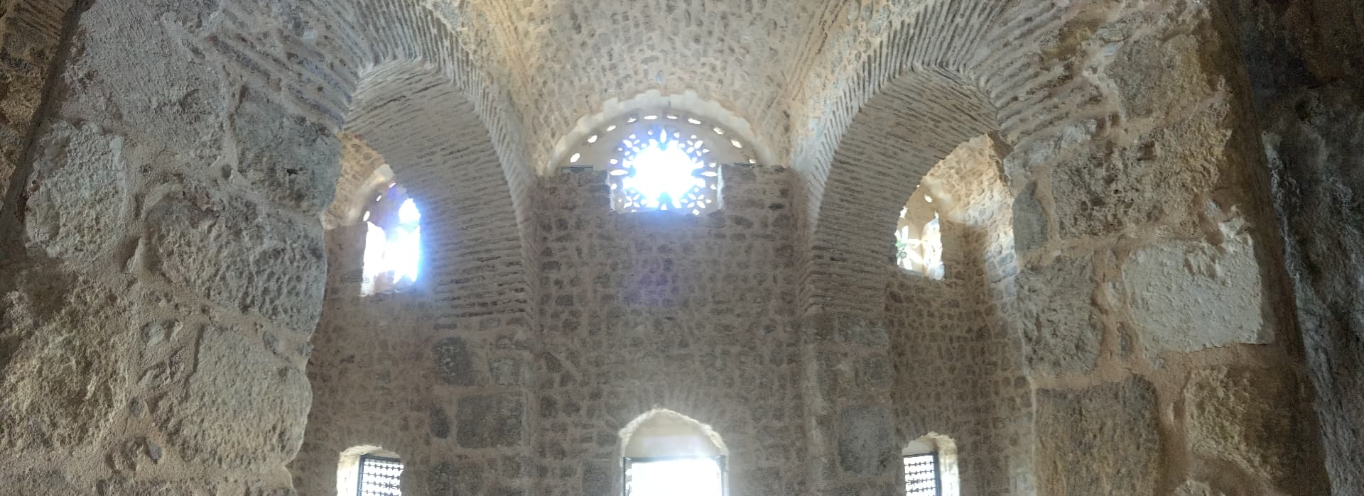 Stone vaulting and arches carrying the weight of a chamber, light entering through a pierced window