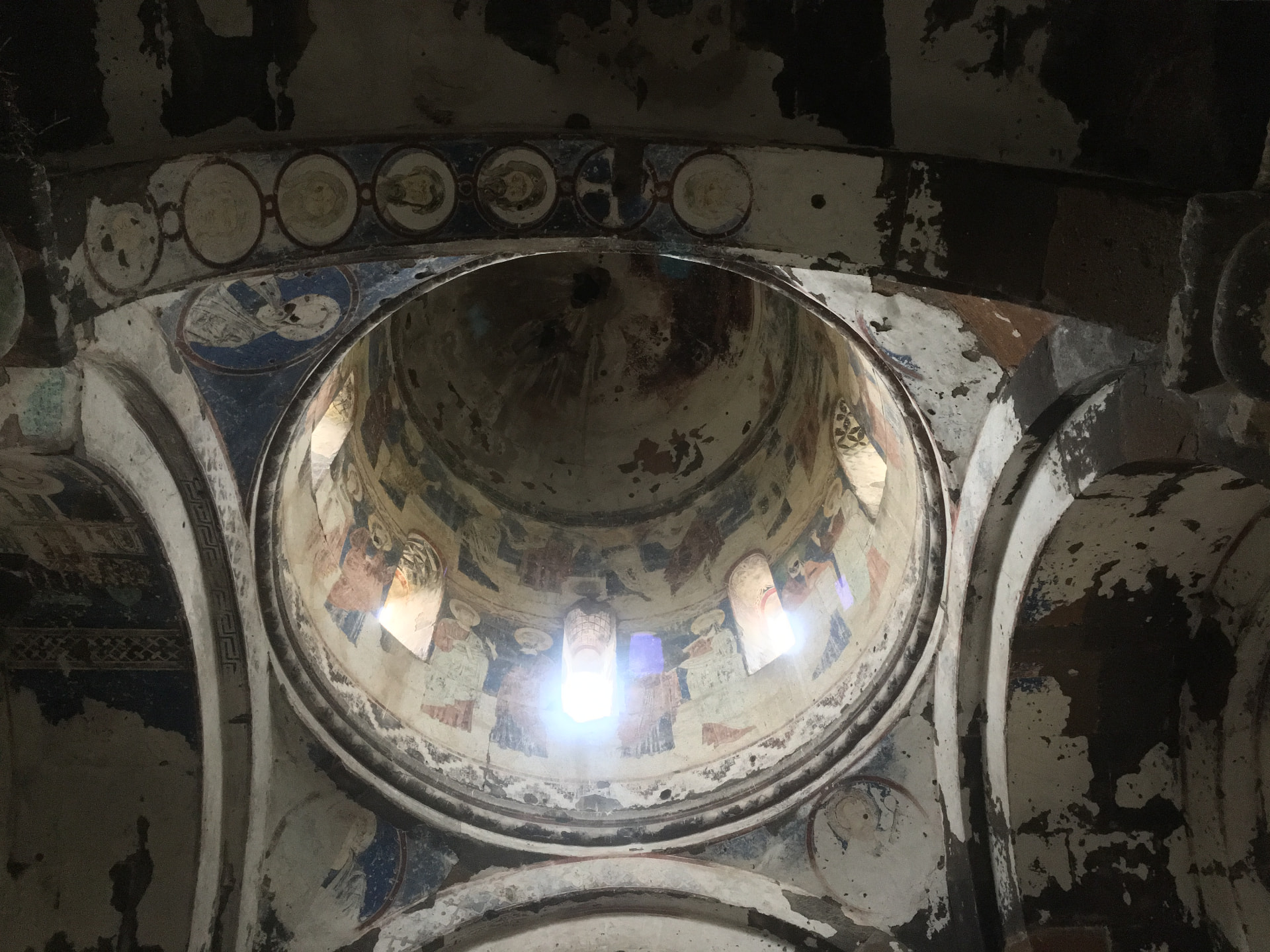 A painted dome of an old church, frescoed figures ringing the drum beneath narrow windows